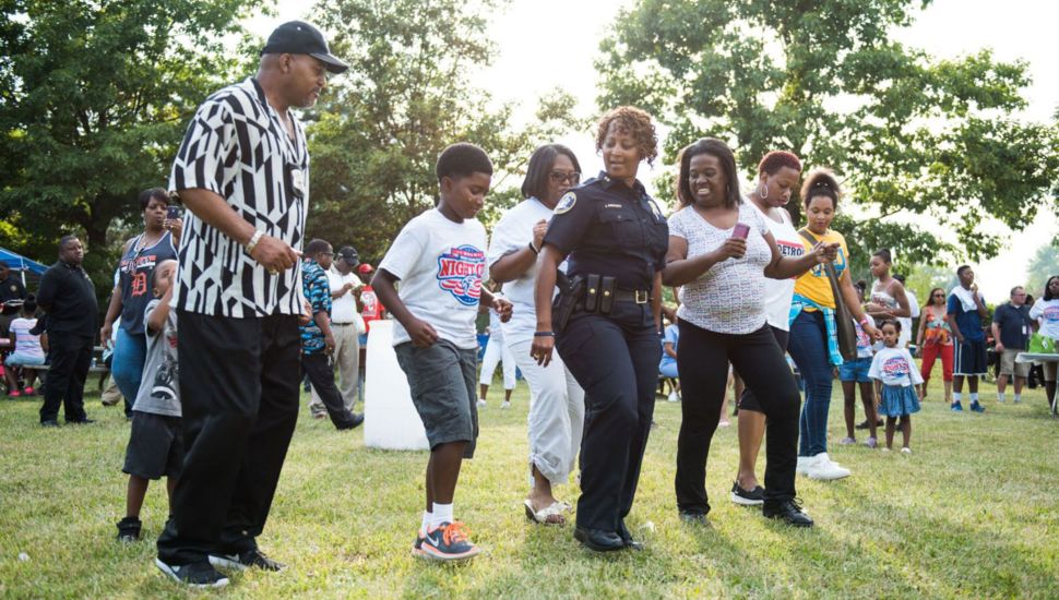 People dancing with police officer at a National Night Out event.