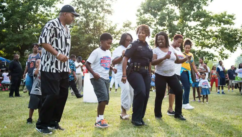 People dancing with police officer at a National Night Out event.