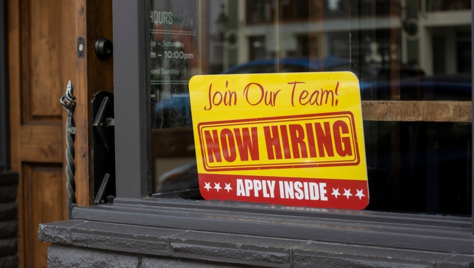 Now hiring sign in store window.
