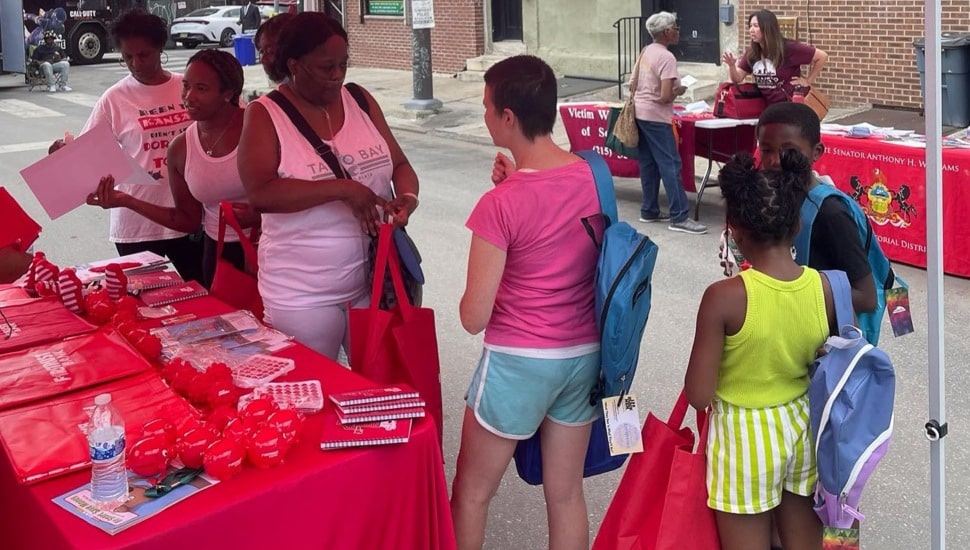 People stand underneath a bank's promotional tent at a community fair.