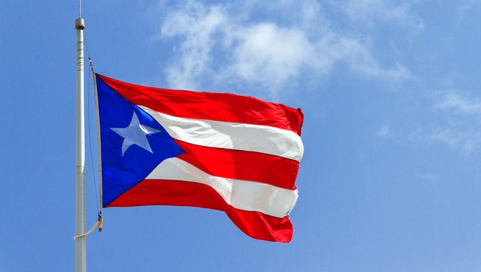 Puerto Rican flag against blue sky.