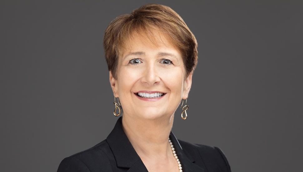 Headshot of middle-aged woman with brown and dark suit jacket.