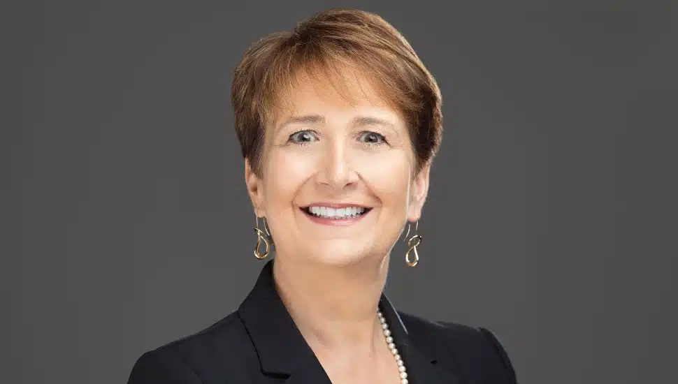Headshot of middle-aged woman with brown and dark suit jacket.