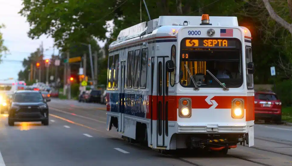 SEPTA Trolley with cars driving behind it.
