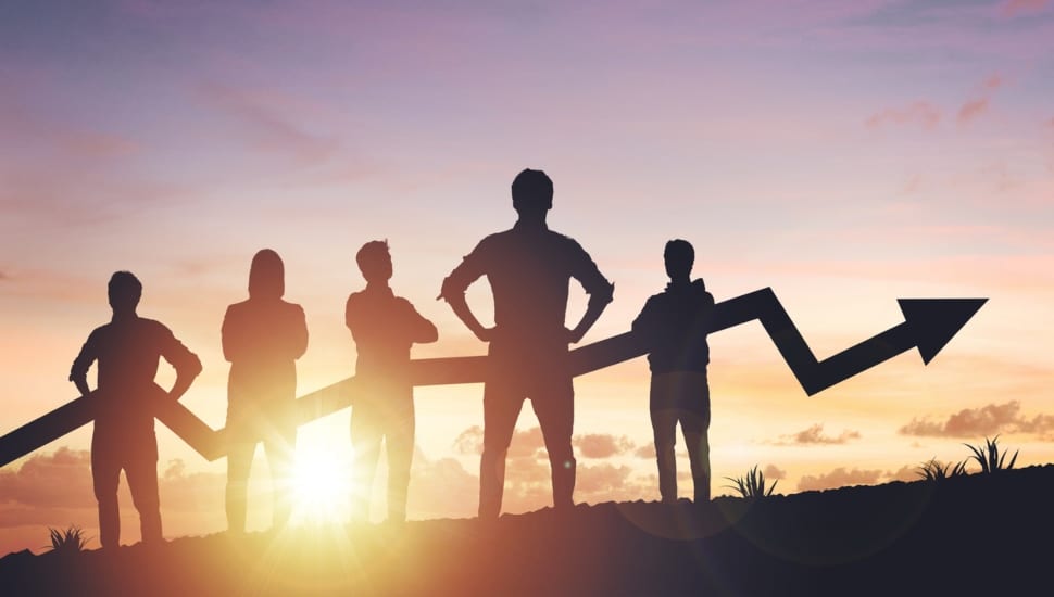 Five people standing in a group at sunset with an arrow in front of them gradually rising.