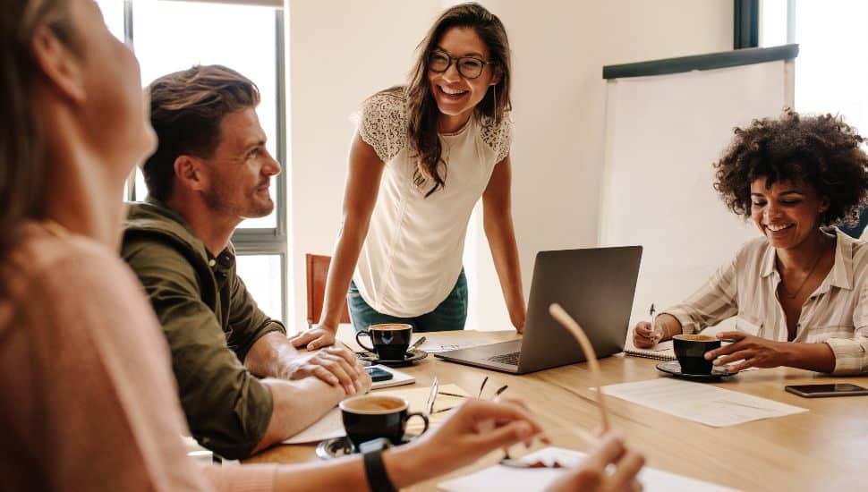 People smiling and working at shared table.