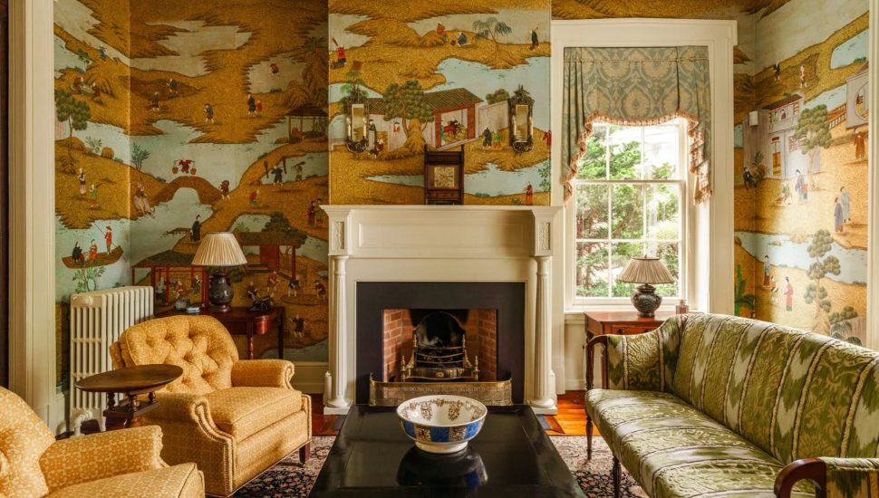 Living room with fire place, chairs and hand-painted wallpaper.