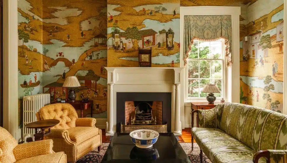 Living room with fire place, chairs and hand-painted wallpaper.