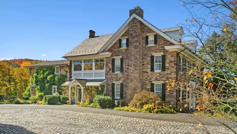 Large stone colonial with a stone walkway in the fall.