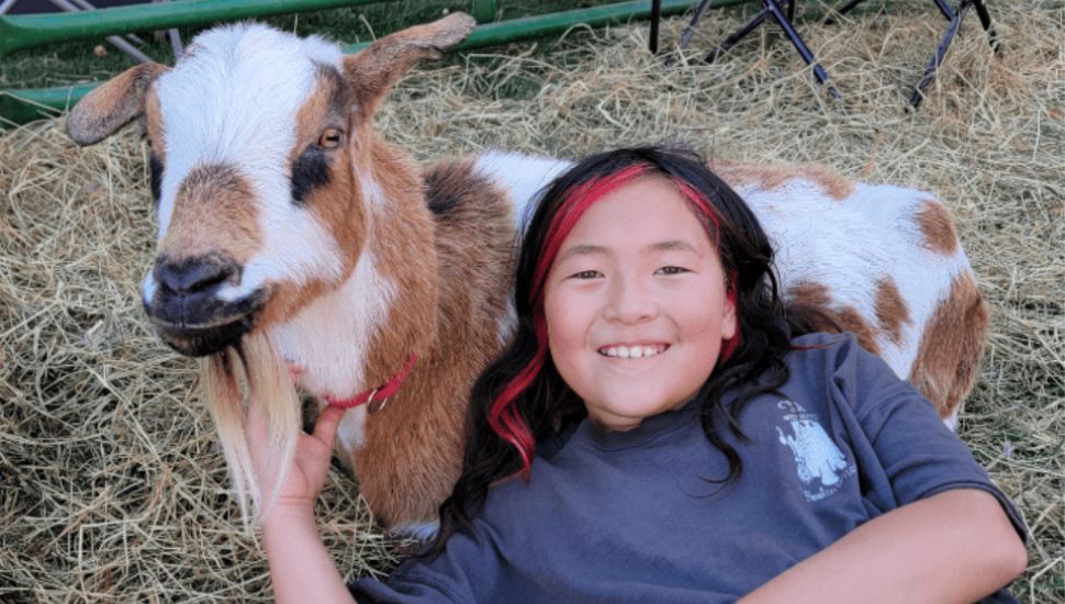 Girl sitting with goat.