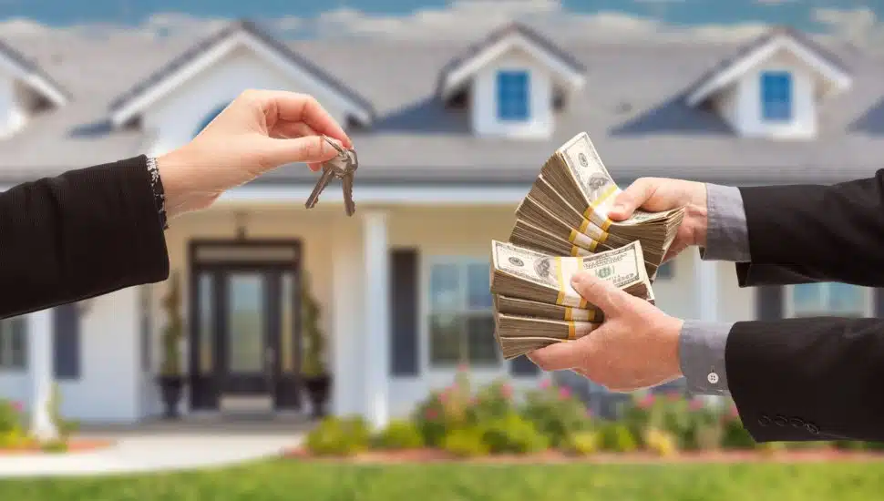 Real Estate Agent Handing Over House Keys for Stacks of Money.
