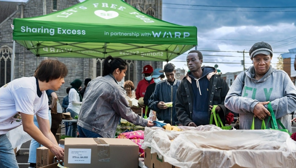 People pick up fresh produce from a distribution tent.