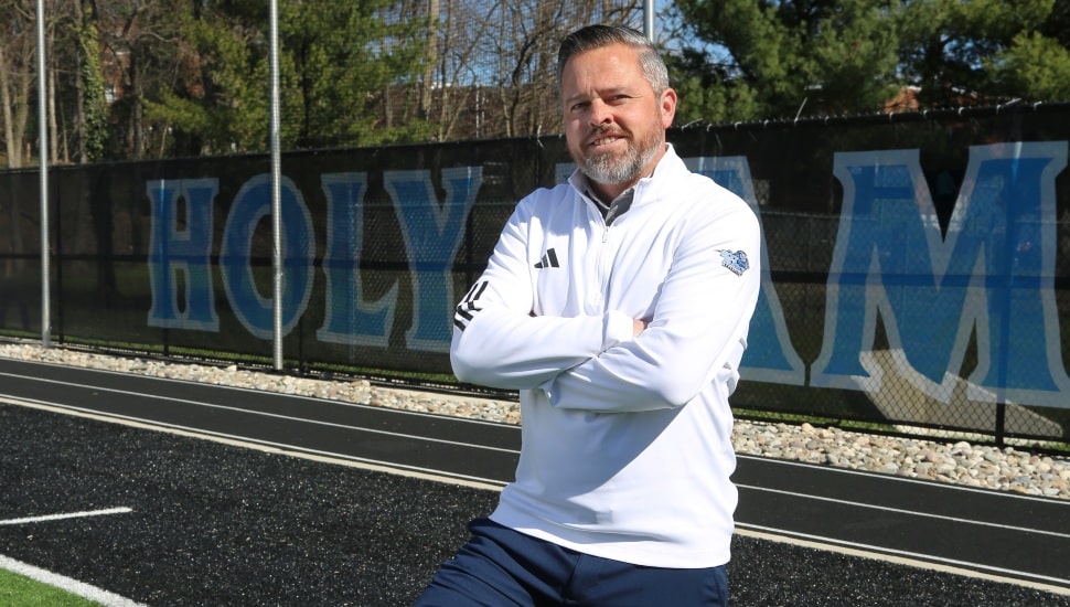 Middle-aged man in white quarter-zip folds arms and poses for picture.
