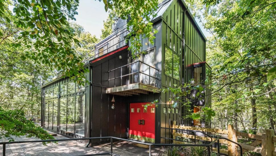 Contemporary home surrounded by trees with floor-to-ceiling windows.