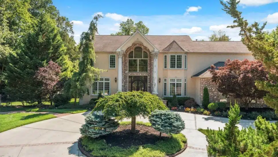 Large colonial with marble columns and a circular walkway.