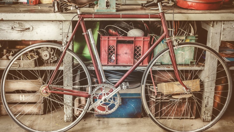 Vintage racing bycicle in front of an old work bench with tools in a garage.