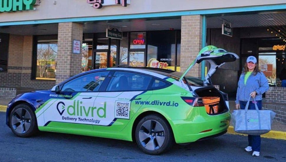 A Dlivrd driver loads food into their branded car.