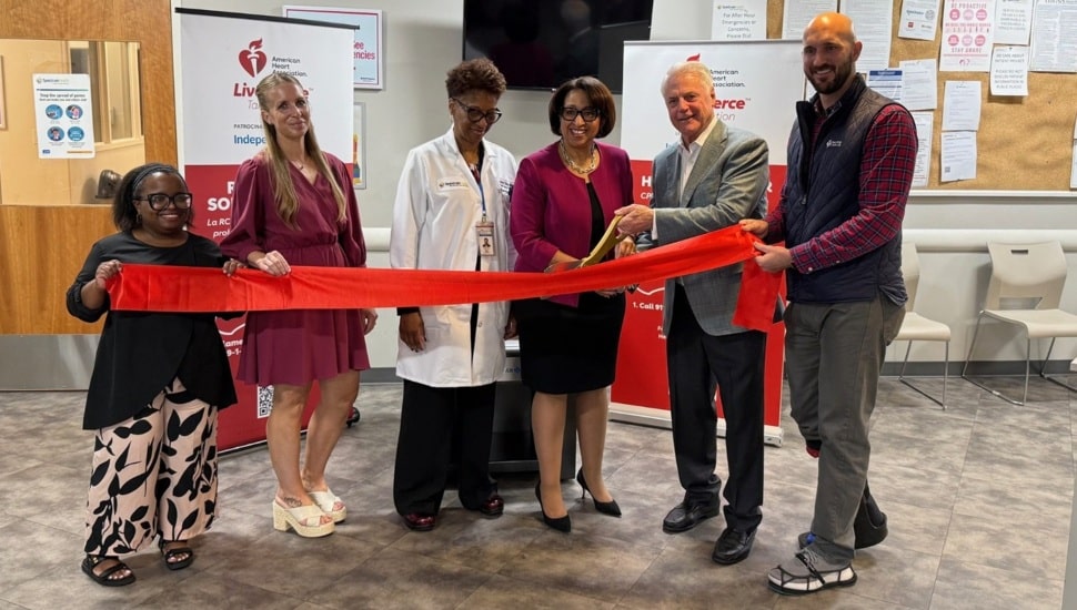 Healthcare and health insurance executives cut giant red ribbon.