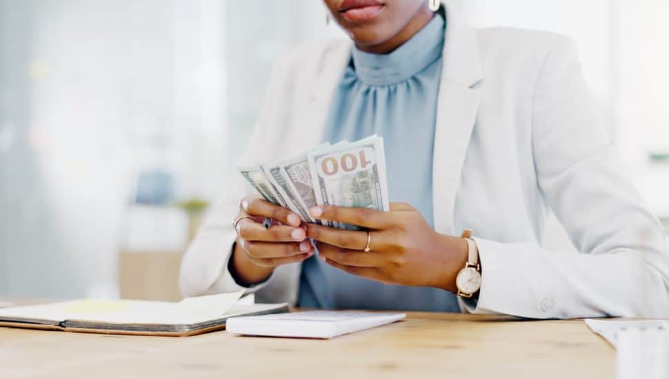 Woman counting hundred-dollar bills.