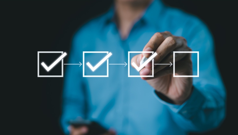 Businessman checks boxes on digital checklist.