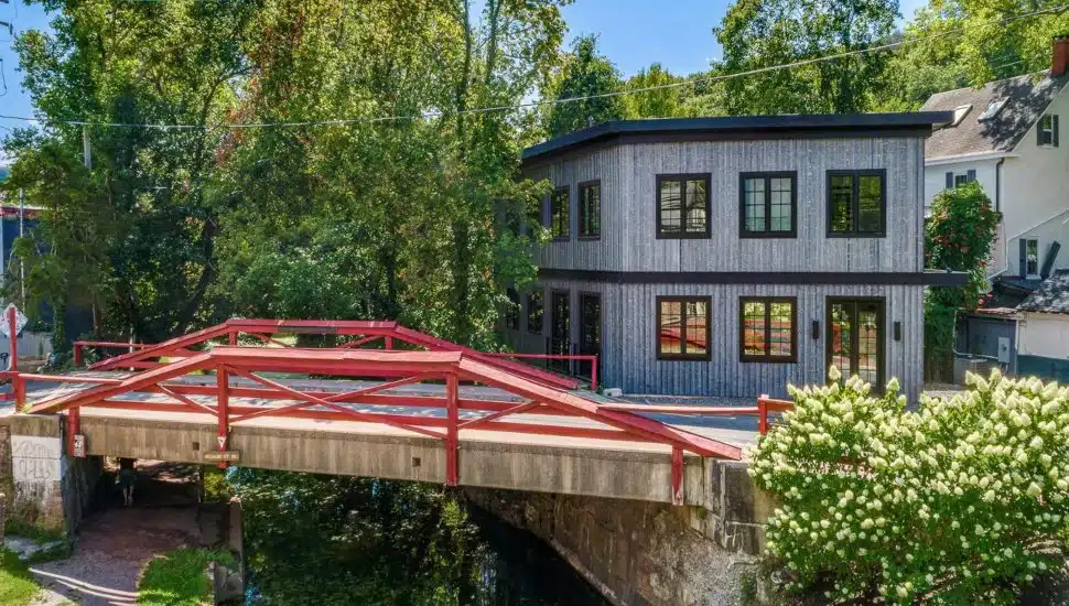Gray contemporary home with a red footbridge in front of it.