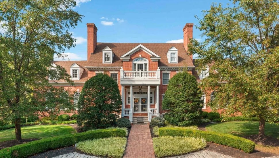 Southern-style colonial with a brick walkway surrounded by trees.