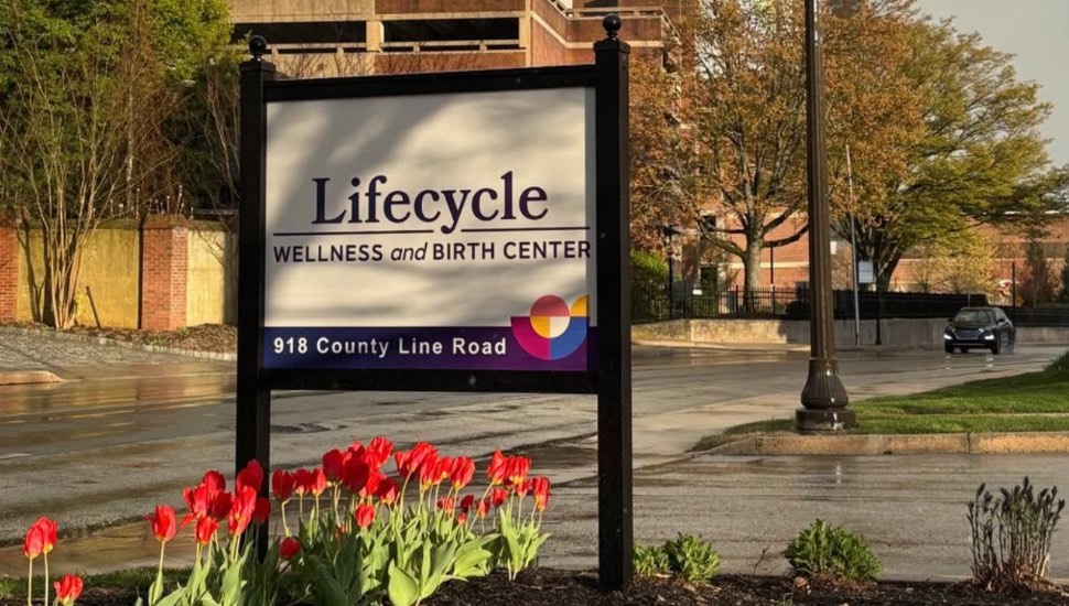 The Lifecycle Wellness sign sits in front of a rainbow.