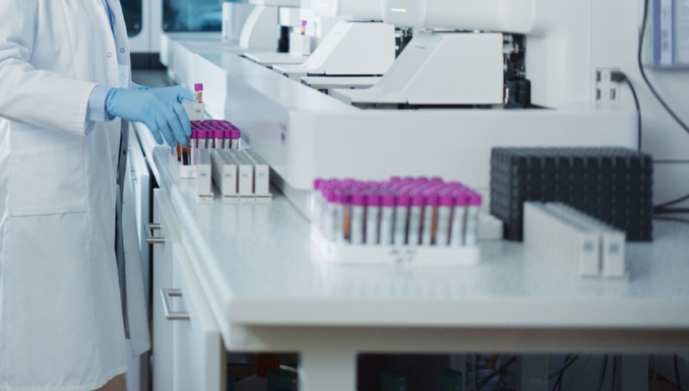 A lab tech reaches for a test tube.