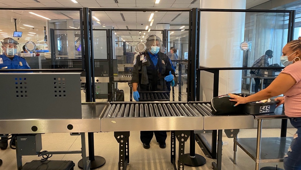 TSA agents check passenger luggage at Philadelphia International Airport.