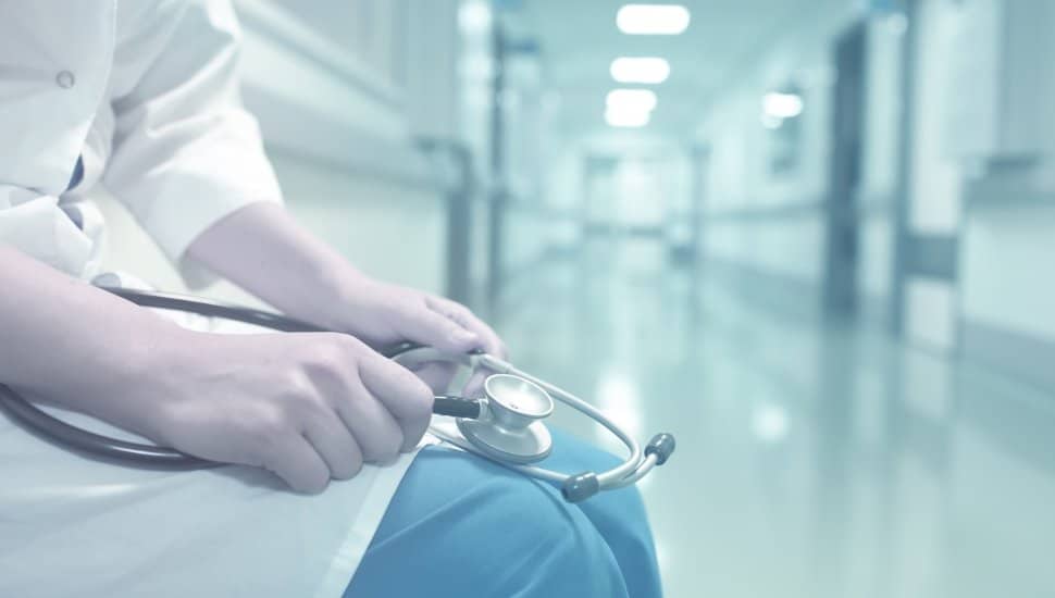 Medical doctor in empty hospital corridor.