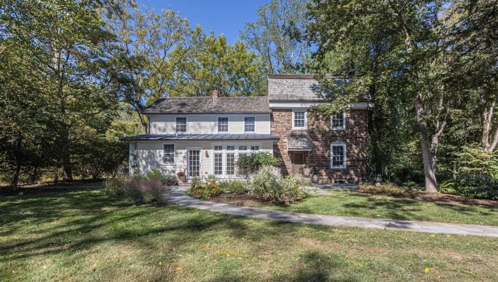 Brick house with addition built, surrounded by trees.