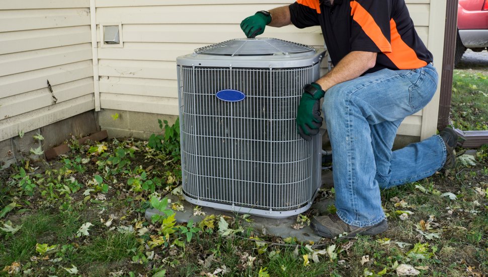 Repairman tightening fan shroud on outside air conditioning unit.