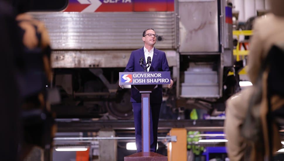 Josh Shapiro speaks at podium with SEPTA train car in background.