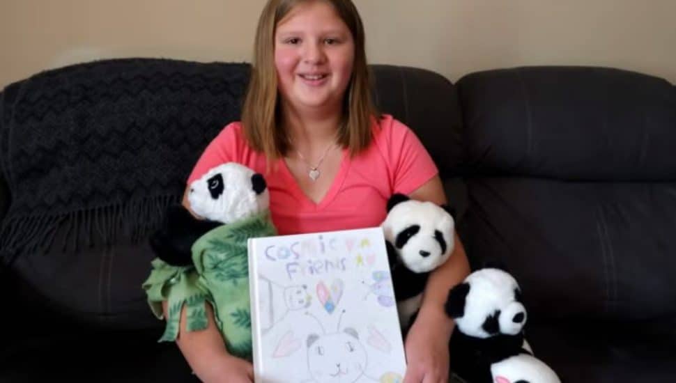 Lizzy Thomas holding her book with her panda stuffed animals.