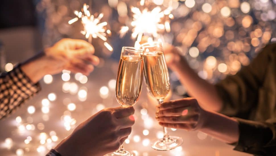 People cheers with champagne, sparklers in background.