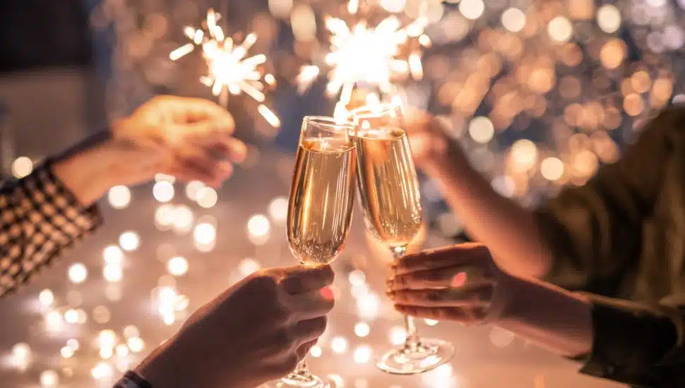 People cheers with champagne, sparklers in background.