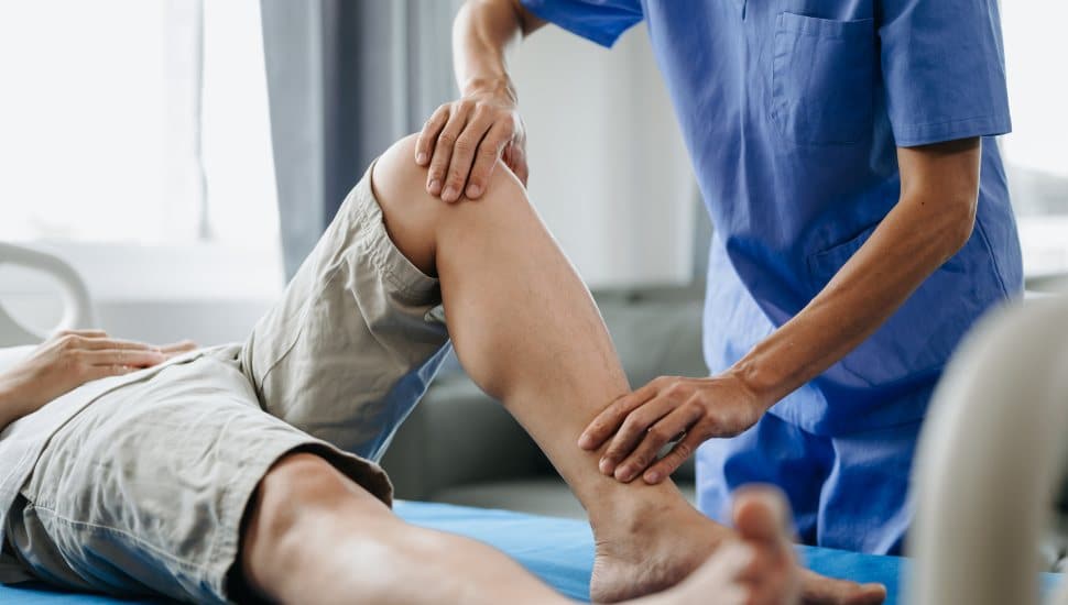Close up of Physiotherapist working with patient on the bed in clinic.