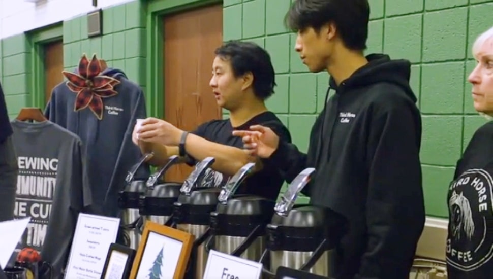Josiah Kessler, the adopted son of Mark and Beth Kessler, serves customer some Third Horse coffee at a community event.