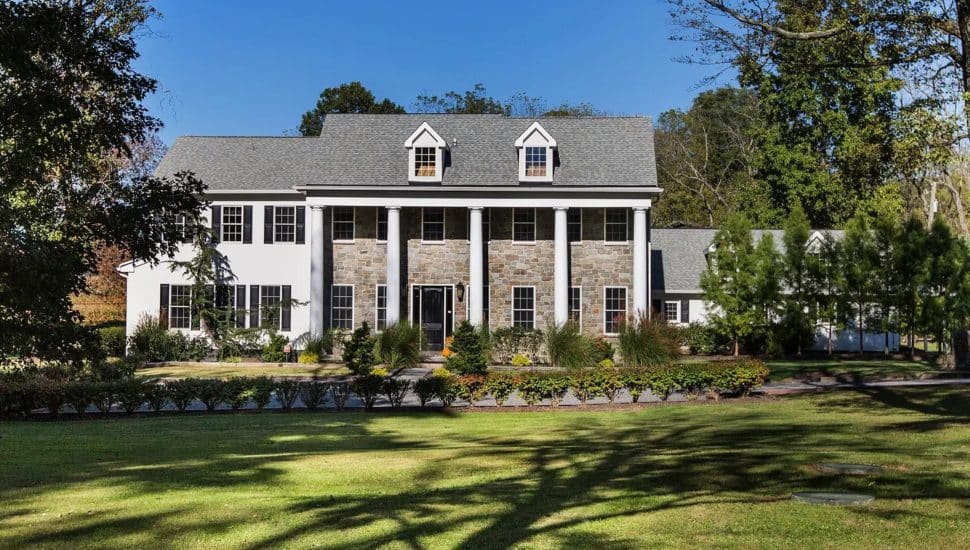 Stone home with white pillars on a manicured lawn.