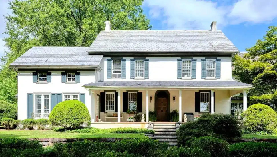 White home with blue shutters and a manicured lawn.