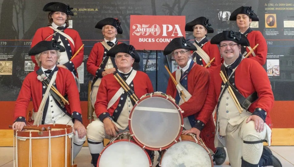 Historical reenactors in front of a Bucks250PA sign.