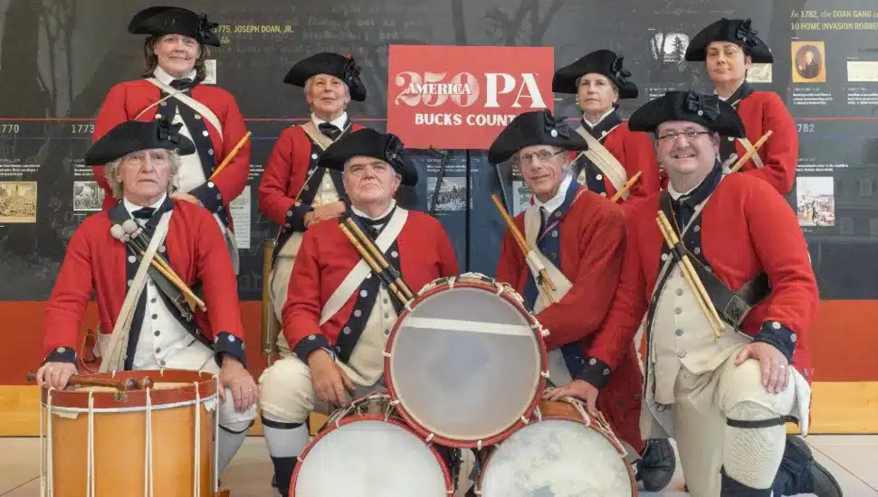 Historical reenactors in front of a Bucks250PA sign.