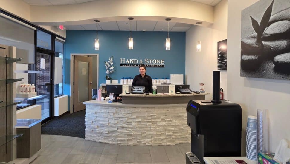Hand & Stone Massage lobby with woman smiling behind front desk.