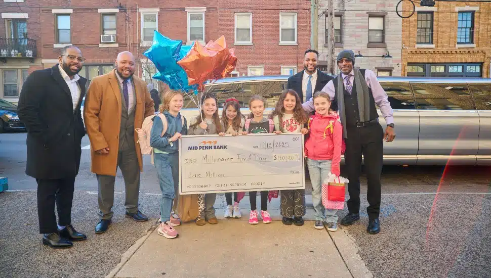 Bank employees pose for picture with elementary school students for check presentation.