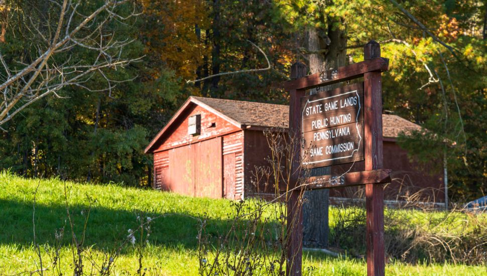 A building on top of a hill in Deerfield Township with a Pennsylvania Game Commission Game Land 86 wooden sign on a sunny fall day.