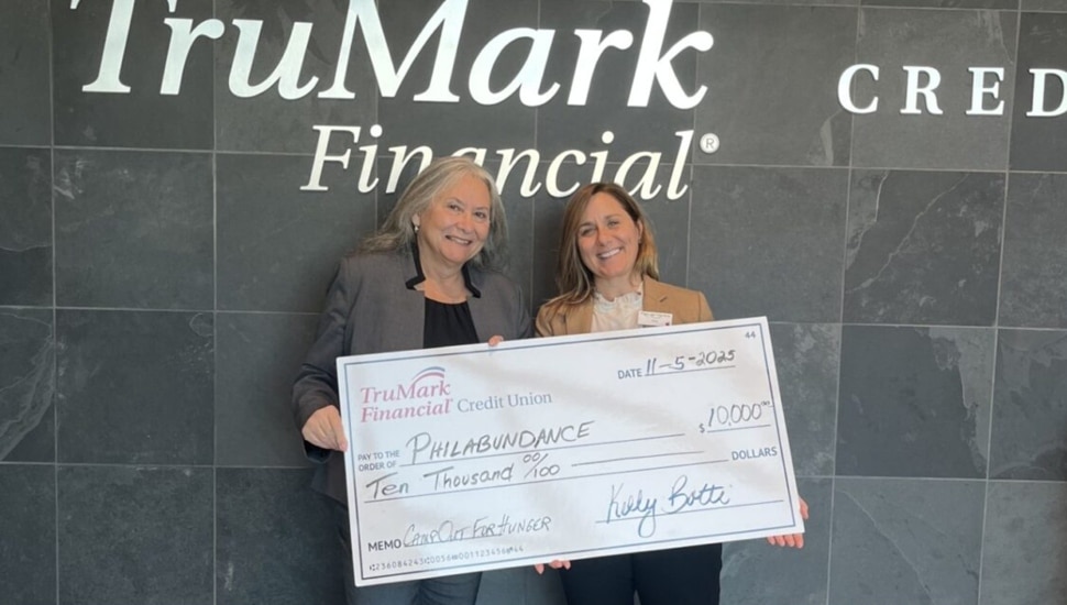 Credit union representative donates check to food pantry.