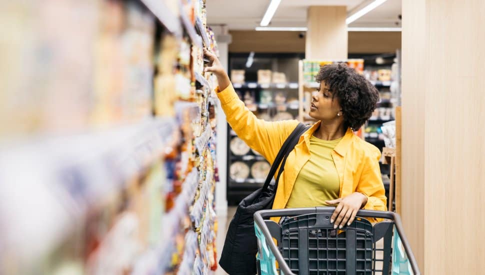 Customer choosing products in supermarket while grocery shopping.