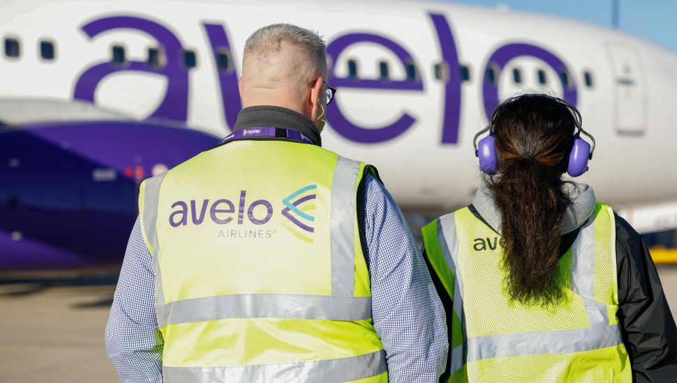 Avelo airline workers on tarmac near plane.