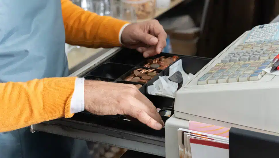 Cashier´s hands searching for change in an open cash register.