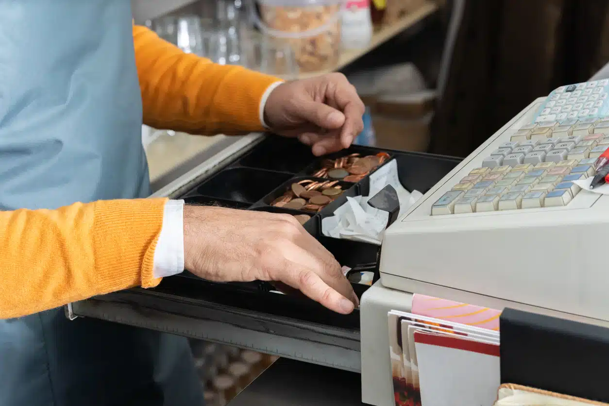 Cashier´s hands searching for change in an open cash register.